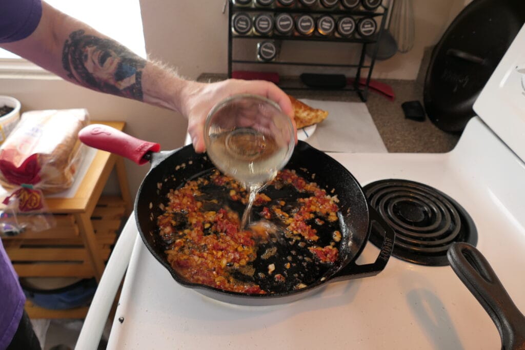 Adding dry white wine to the marry me chicken pan